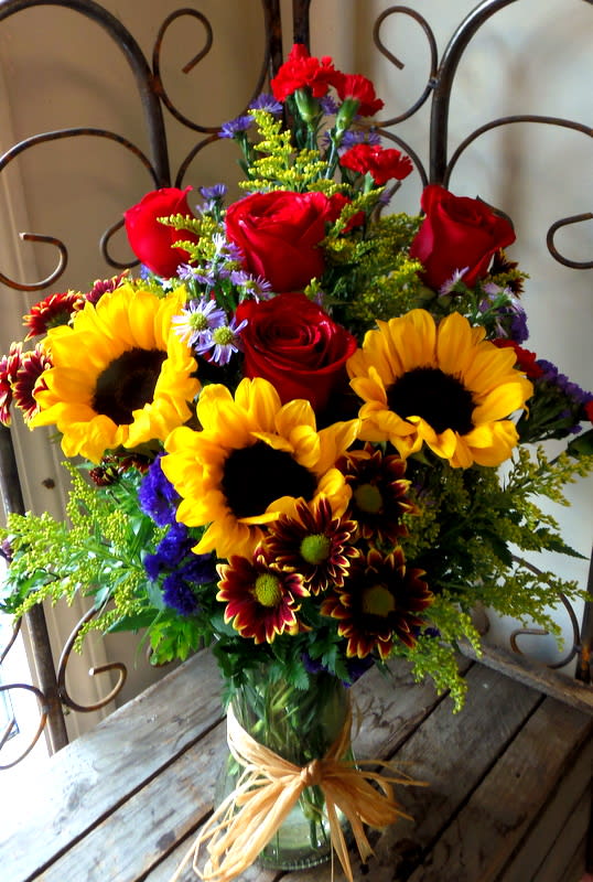 Bouquet of red roses and sunflowers in a glass vase