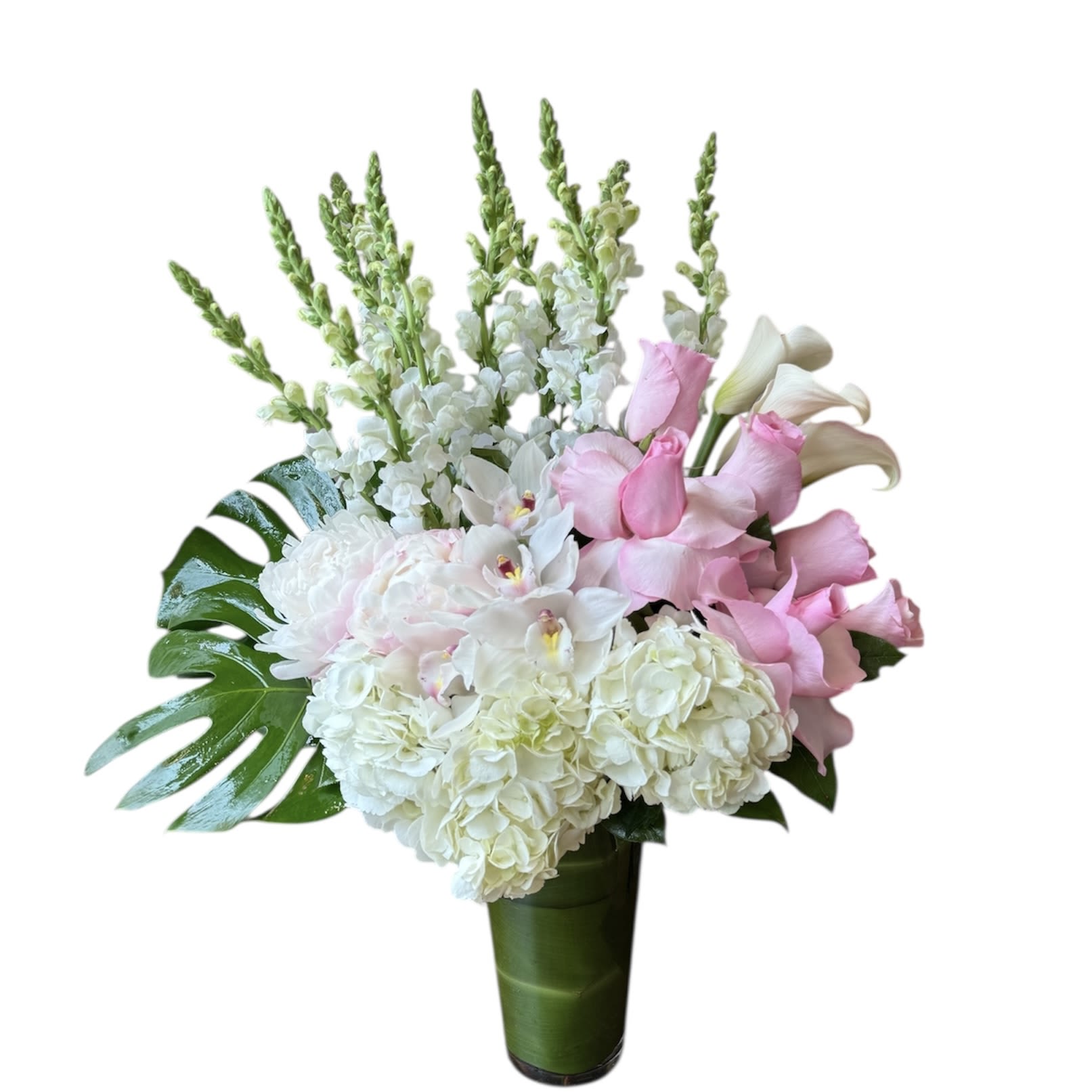 Tall arrangement of white hydrangeas, orchids, snapdragons and pink roses in a glass vase