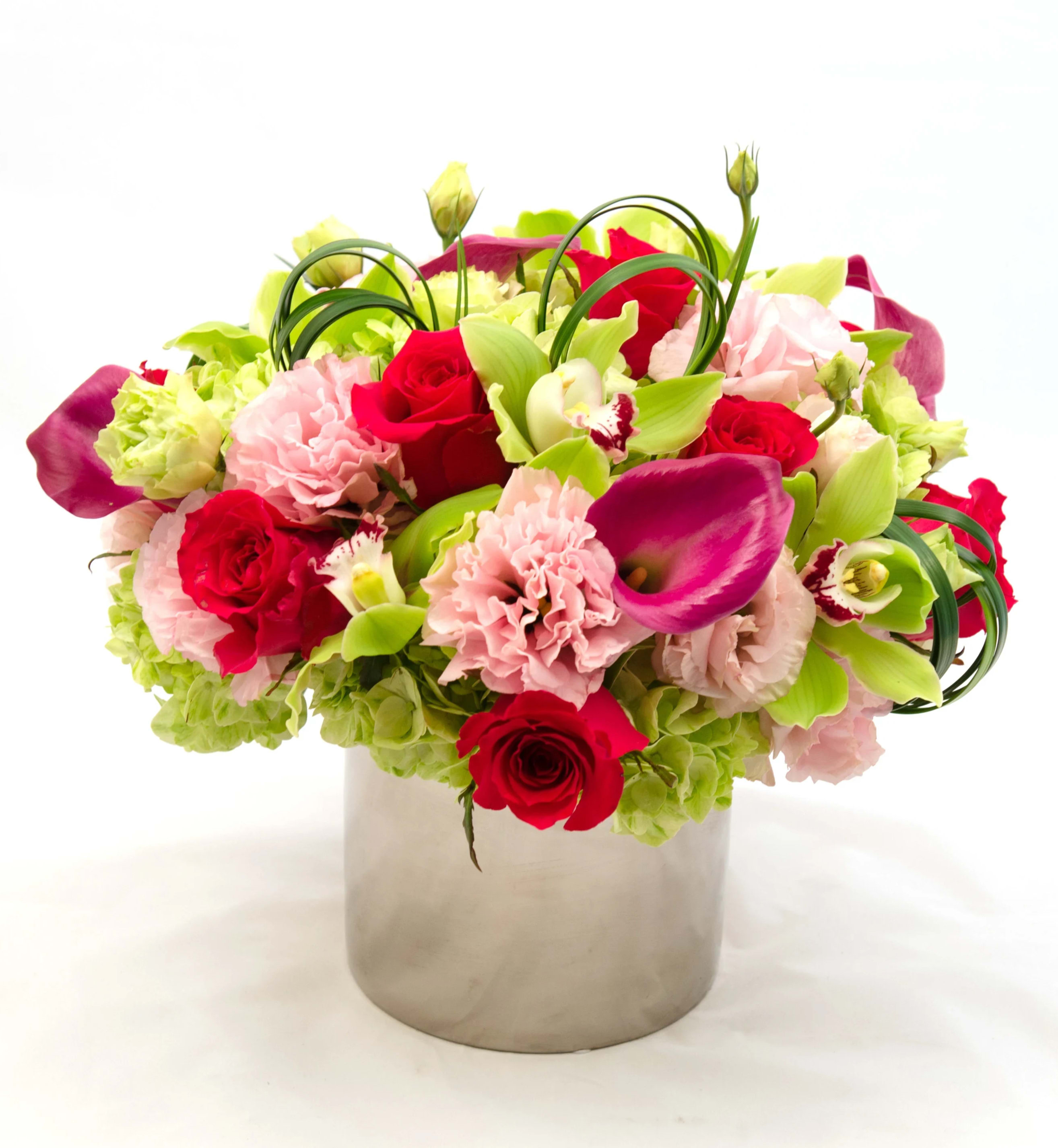 Bouquet of red roses, pink carnations, and green calla lilies in a silver vase
