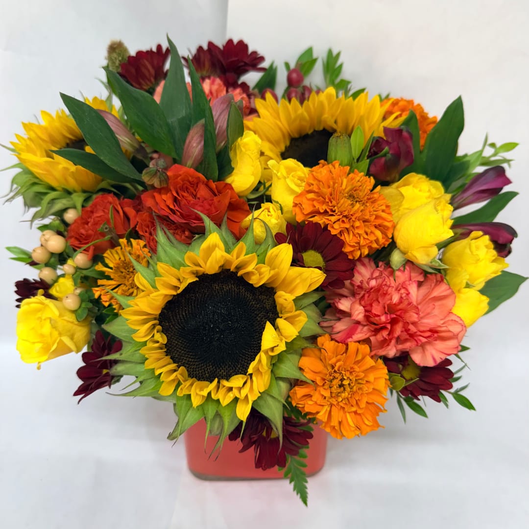 Colorful bouquet with sunflowers, roses, and carnations in a red vase