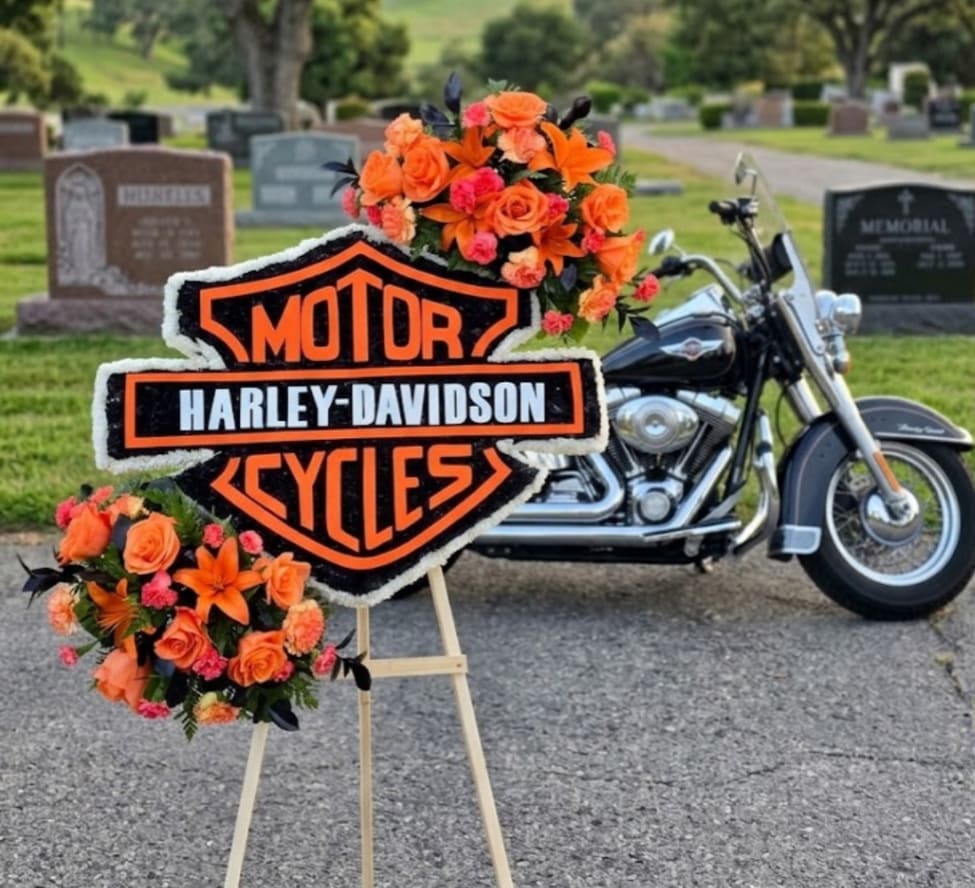 Orange floral tribute on an easel with a Harley-Davidson sign