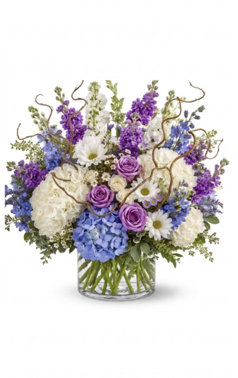Shimmering Colors - A lush summer garden arrangement featuring abundant white and blue hydrangeas, elegant purple stock, lavender roses, and delicate seasonal blooms in a clear glass vase.  *Vase/container may vary depending on availability of stock at time of purchase. *We strive to use the flowers shown whenever possible; however, substitutions of equal or greater value may be made based on seasonal and market availability. 