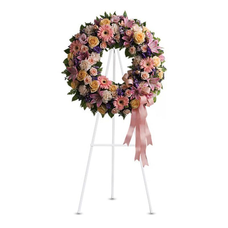 Floral wreath on a white stand with pink ribbon