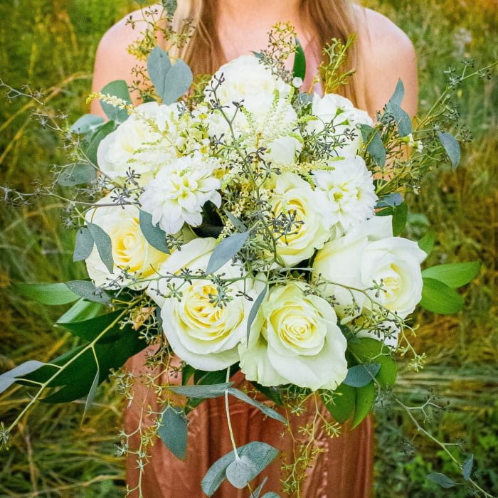 Bride holding a bouquet of white roses and pale blooms with eucalyptus