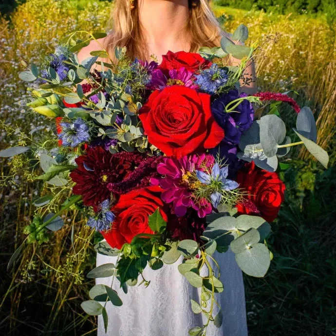Woman holding a bouquet of red roses and purple flowers