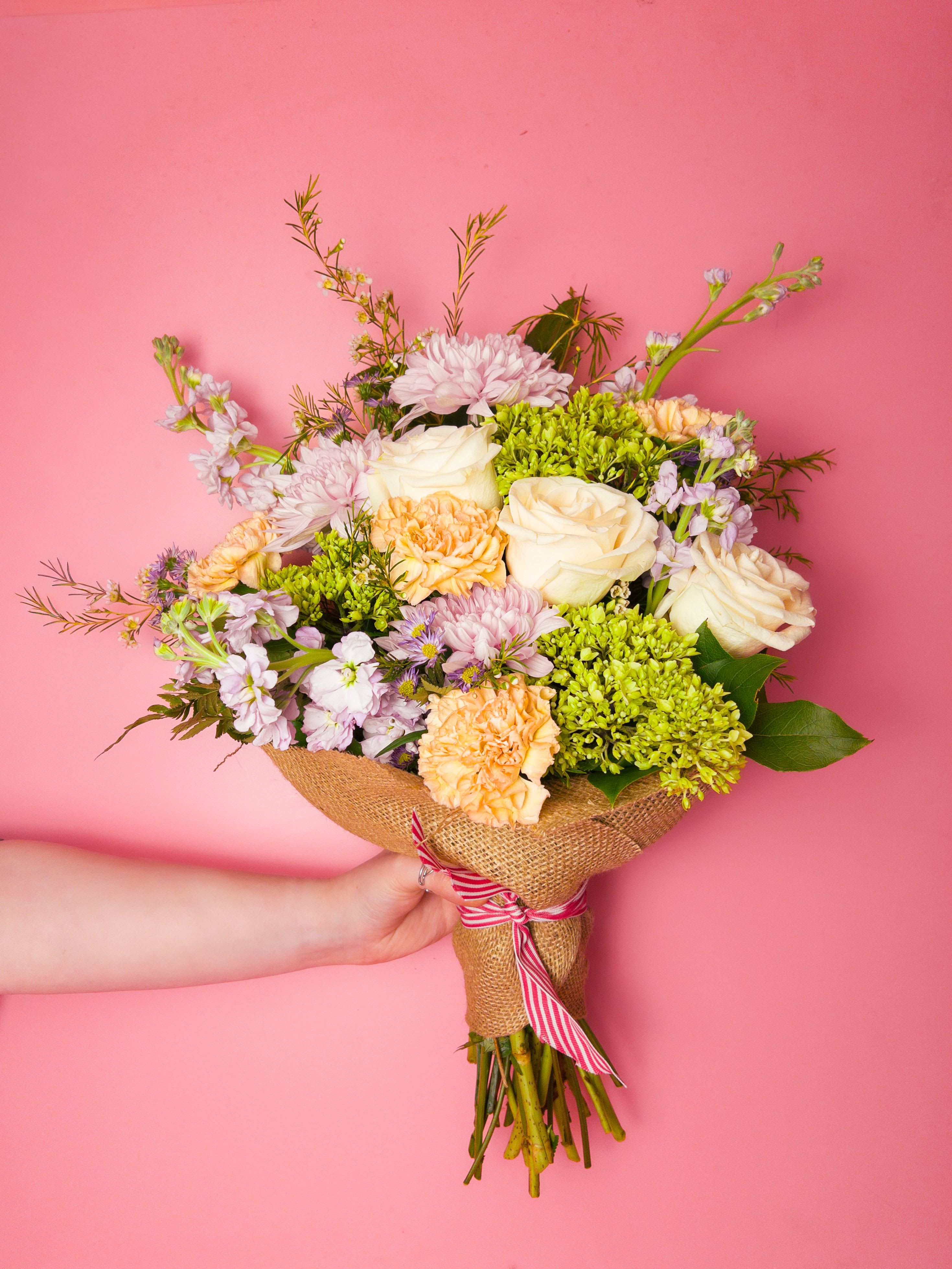 Garden Muse Bouquet - Soft peach, pale purple, creamy white and fresh green come together in a garden-style hand-tied bouquet that feels like a spring morning - perfect as a birthday surprise, get well wish, or a thoughtful thank-you arrangement. This flower arrangement's airy look and approachable color story is made to make the person you're thinking of feel cherished and seen; the soft palette reads as gentle celebration for moms, friends, or anyone who favors quiet, natural beauty.  The arrangement features a loose mix of blooms wrapped and finished with a ribbon. Because we prioritize color and seasonal freshness, exact varieties may vary to keep the peach, purple, white and green palette consistent; sizes are scaled to a hand-tied design that looks full without being fussy. Care for the bouquet by trimming stems and refreshing water every couple of days to extend bloom life.  Ordering from The Flower Cart means easy flower delivery in Baltimore and a reliable way to brighten someone's day-whether for celebrations, everyday gifting, or to say thank you. If you need it delivered directly, our team can handle special requests and ensure the color-forward look arrives just as pictured.