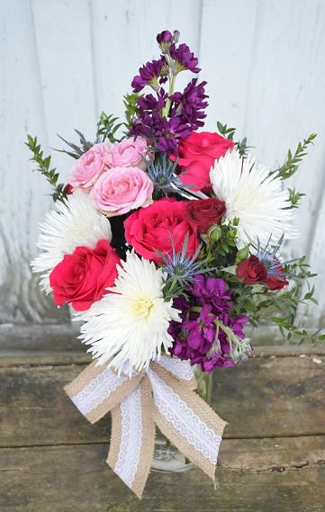 Bouquet of pink and red roses with white daisy-like blooms in a vase
