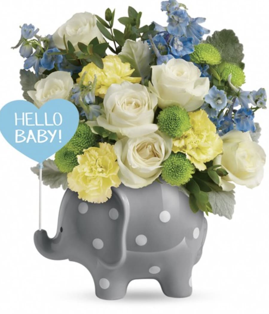 White and blue flowers in a gray polka-dot elephant container with a "Hello Baby!" sign