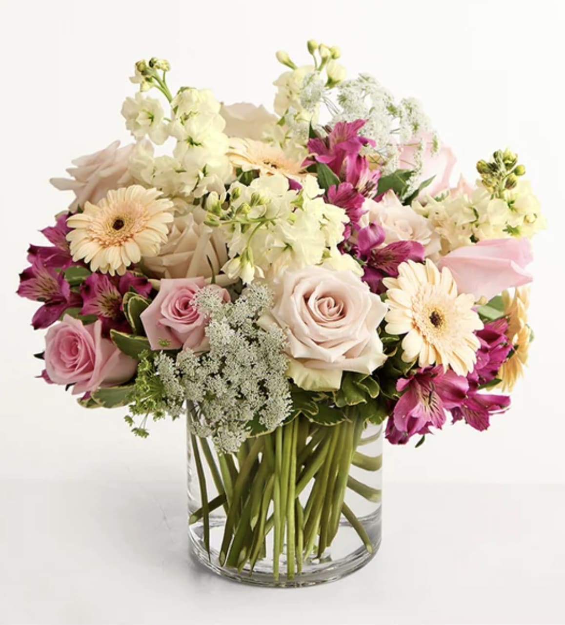 Mixed pink and cream flowers arranged in a clear glass vase