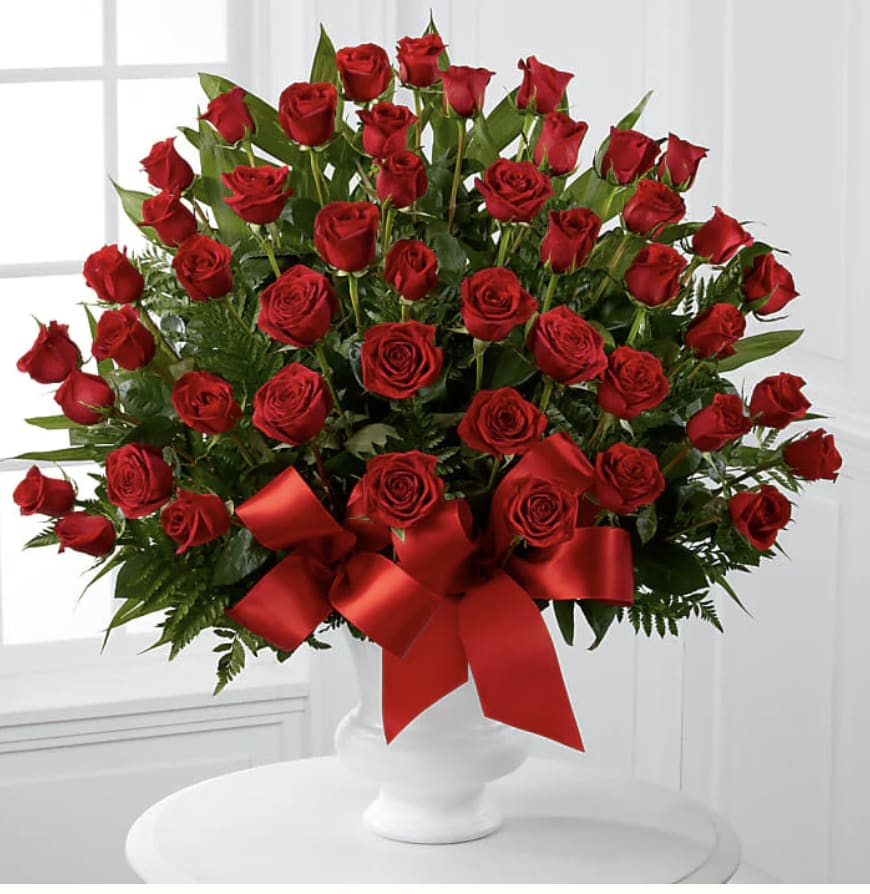 Large bouquet of red roses in a white vase with a red ribbon