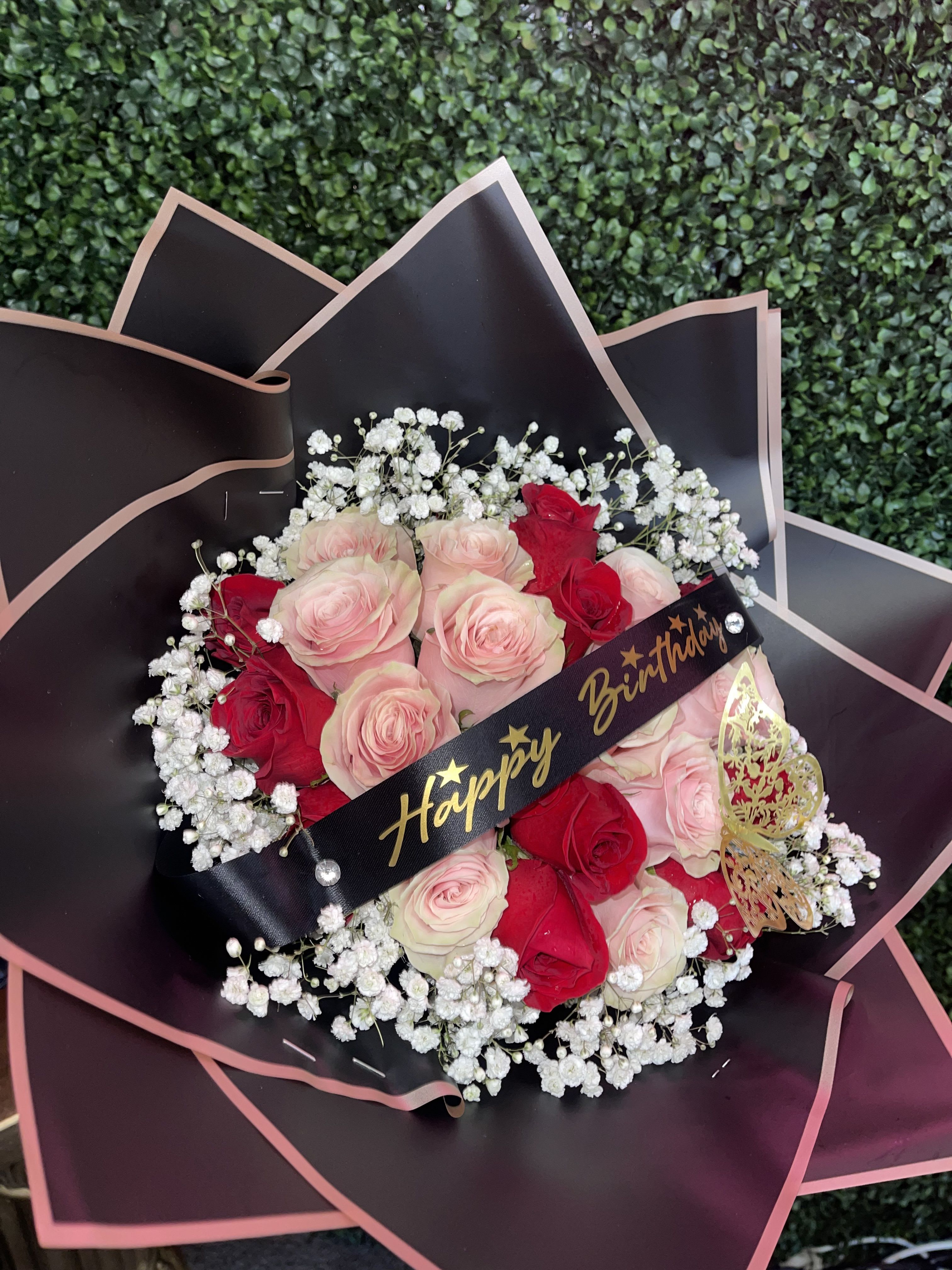 Bouquet of pink and red roses with baby's breath and a birthday ribbon