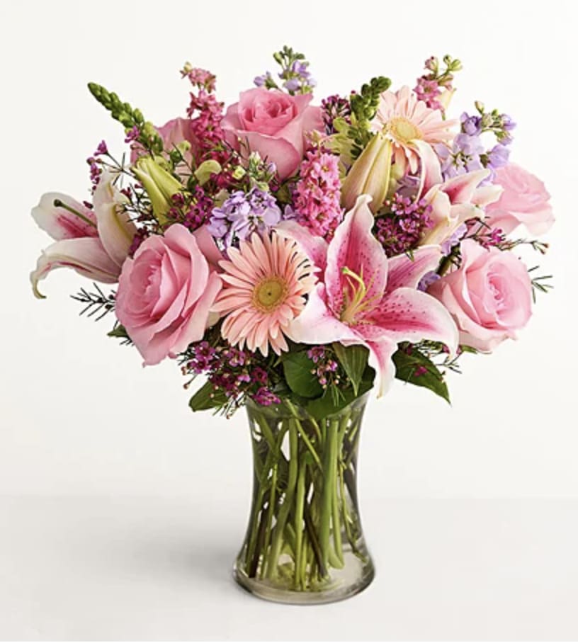 Pink roses and lilies arranged in a clear glass vase