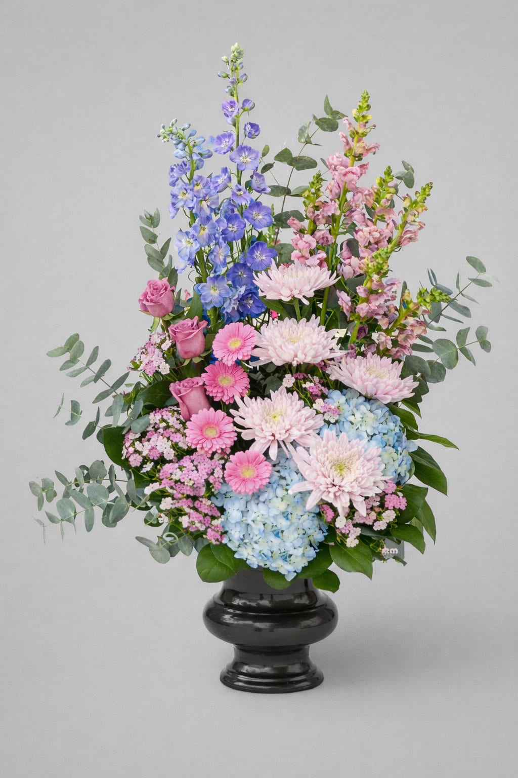 Tall pastel flower arrangement in a black urn vase