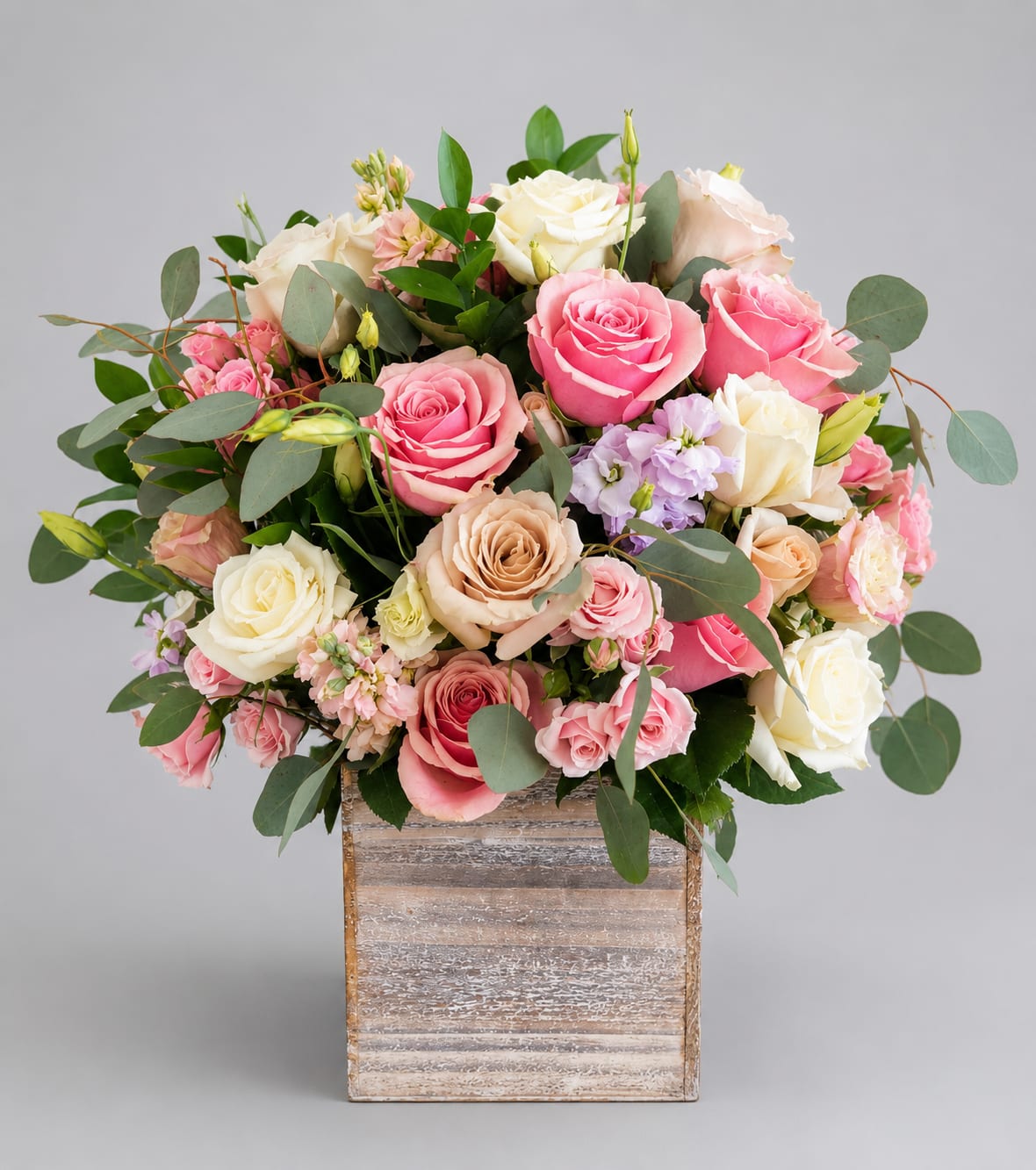 Pink and cream roses arranged in a wooden box
