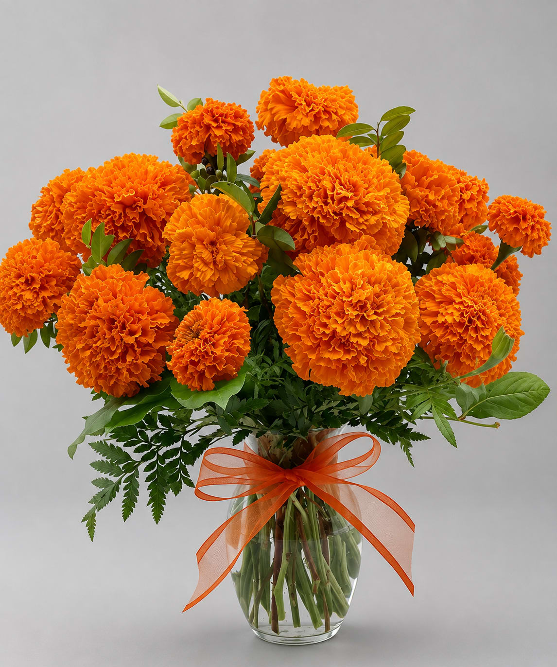 Orange marigold bouquet in a clear glass vase with an orange ribbon
