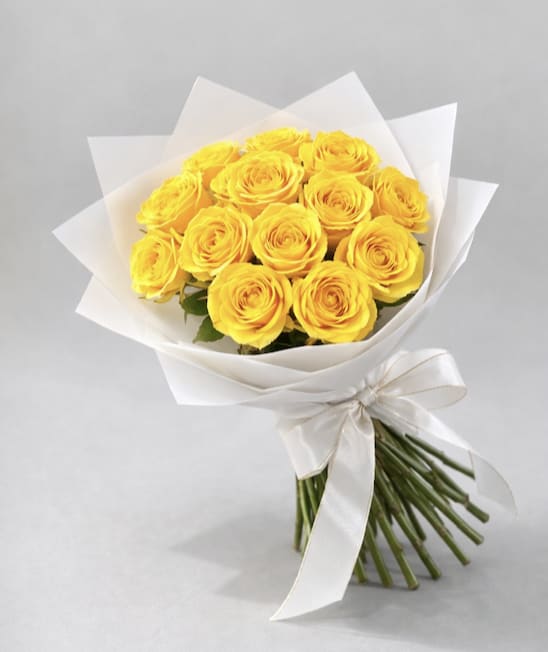 Bouquet of yellow roses wrapped in white paper with a ribbon