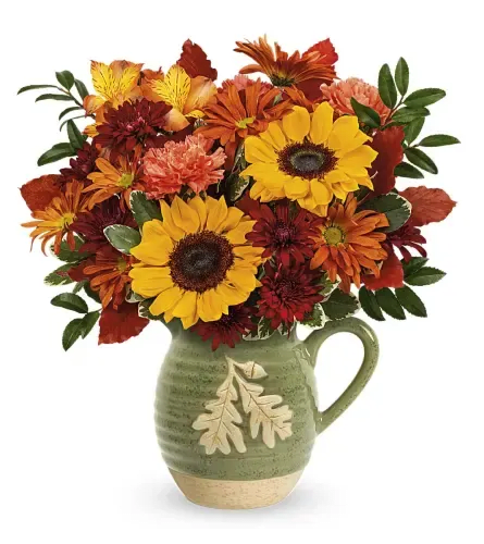 Acorn Pitcher  - Autumn Acorn Pitcher by Teleflora - Standard. An arrangement by Sueppel's Flowers.Description Bursting with fall blooms, this glazed stoneware pitcher of autumn cheer is a vase now, a food-safe serving favorite for years to come 