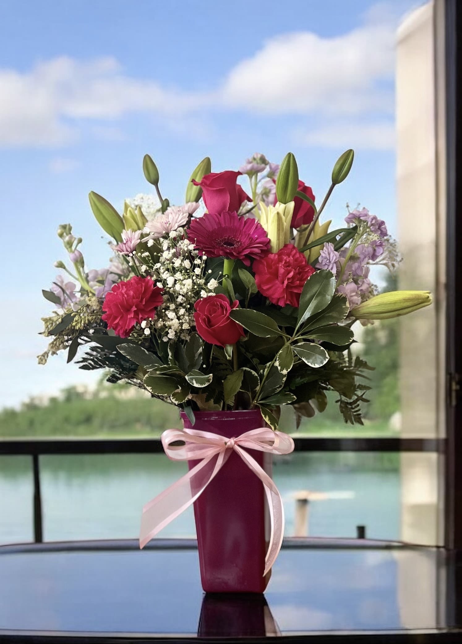 Pink and purple mixed bouquet in a magenta vase with a ribbon