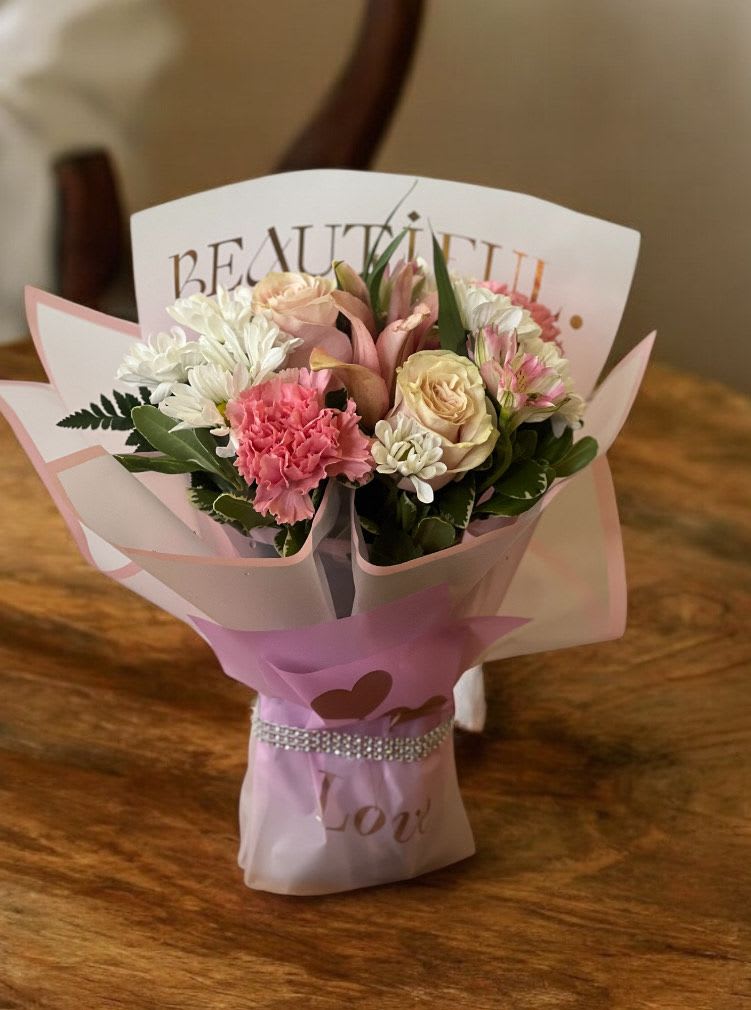 Pink and white bouquet with roses and carnations wrapped in pastel paper
