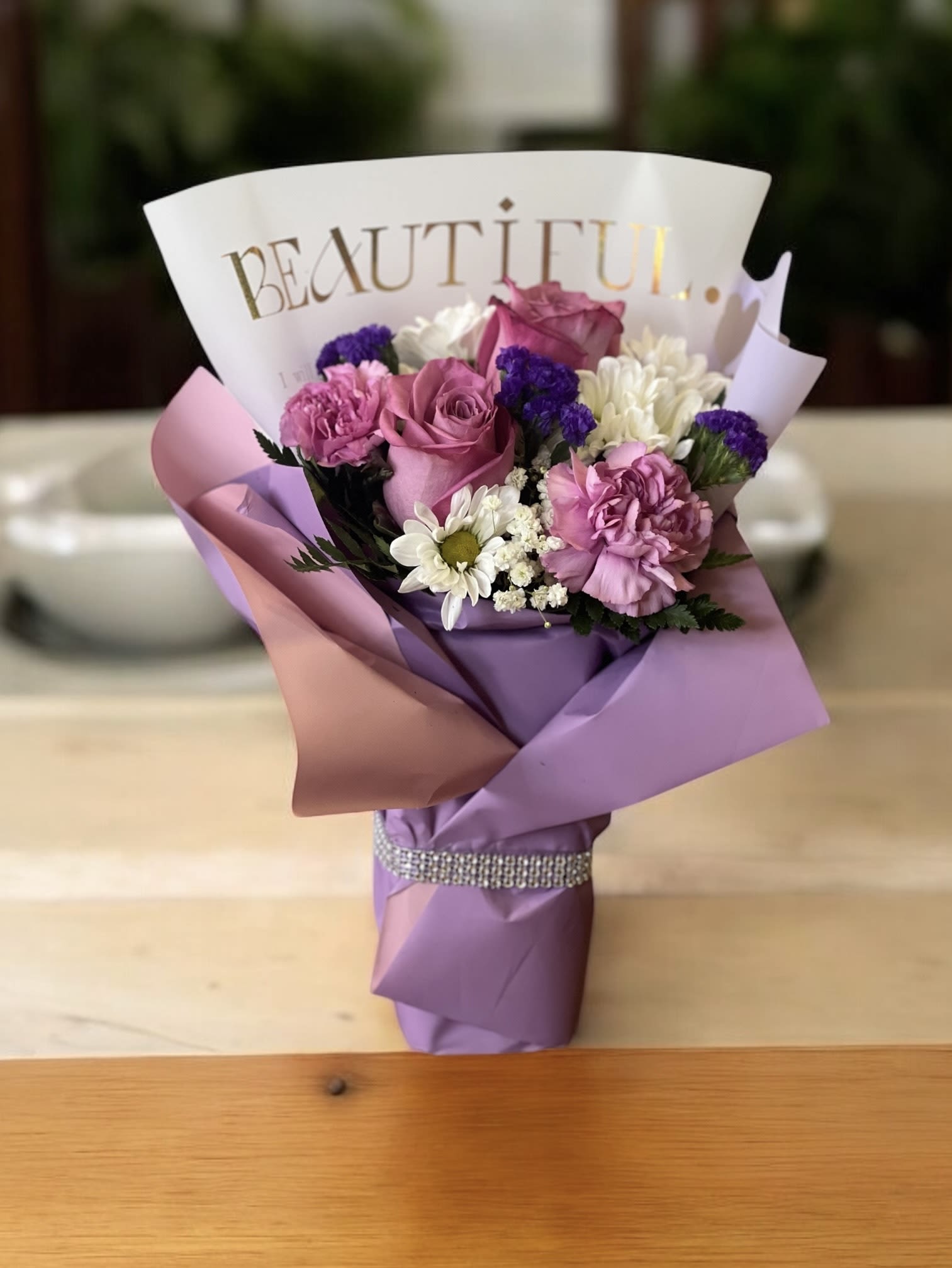 Pink and purple bouquet with roses, carnations, and daisies wrapped in paper