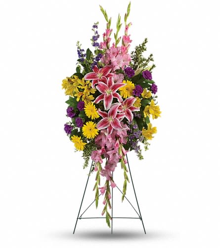 Standing floral spray with pink lilies, yellow daisies, and purple flowers on an easel