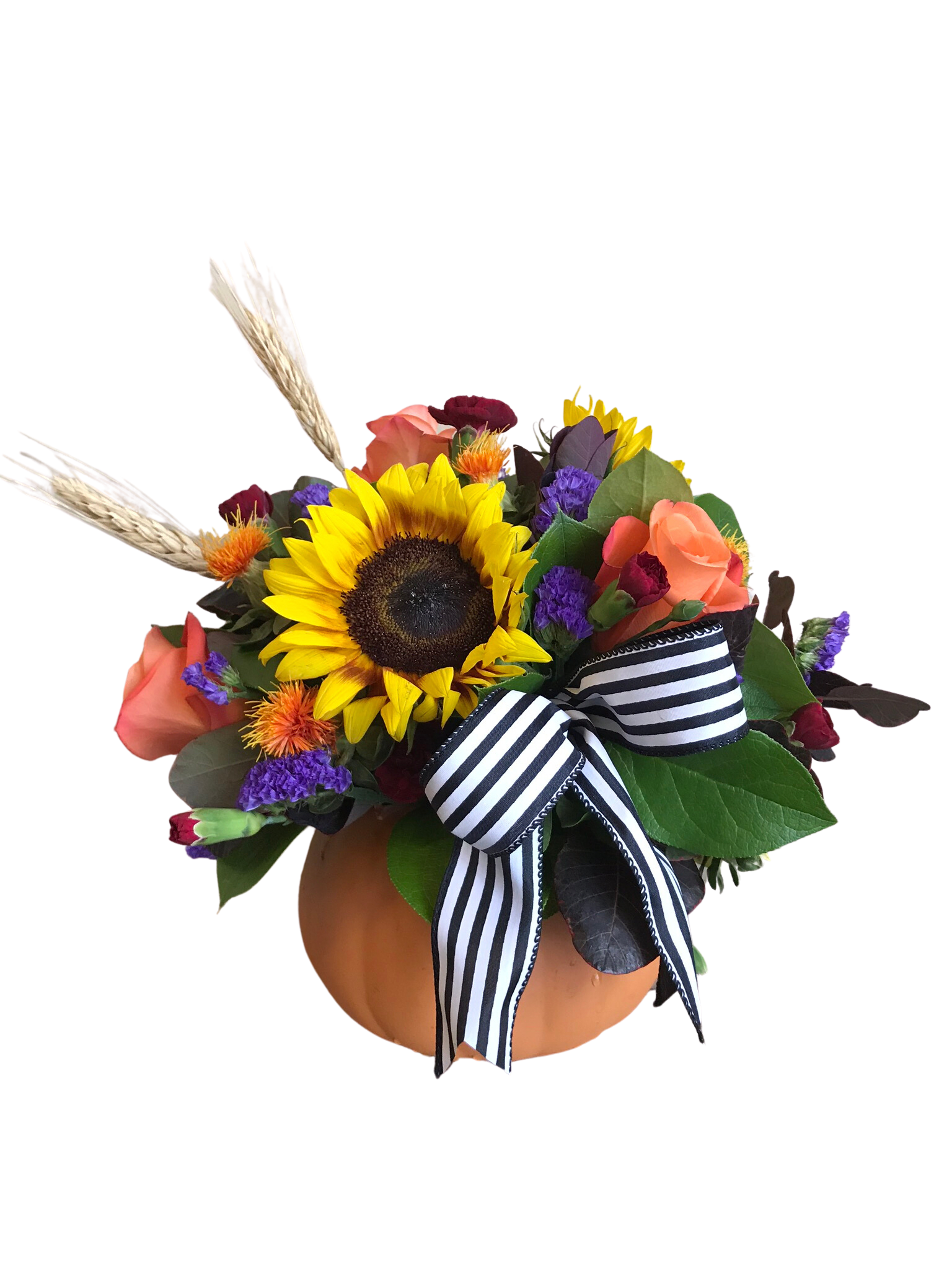 Sunflower and rose arrangement in a pumpkin container with a striped ribbon