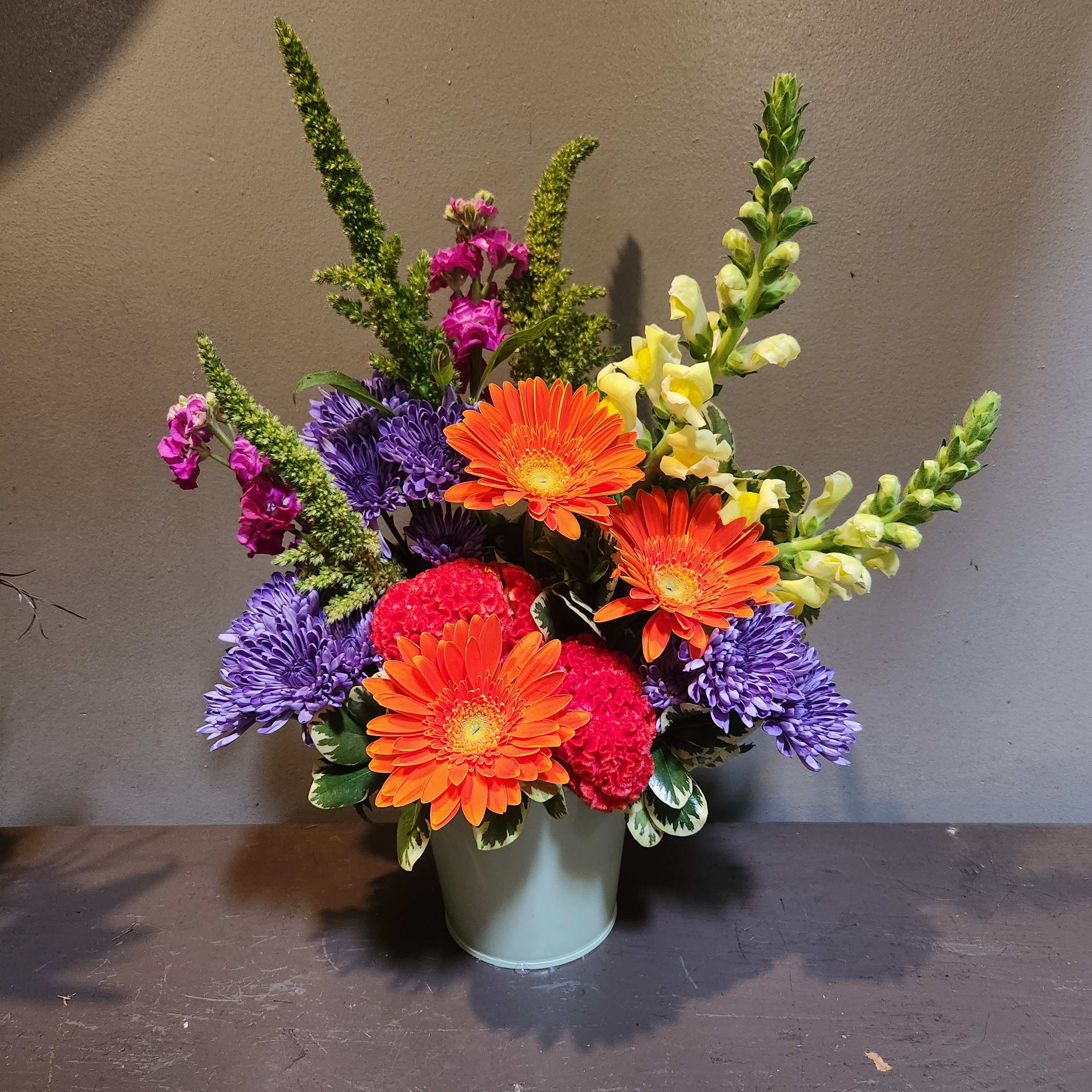 Colorful mixed flower arrangement in a pale green vase