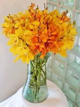 Yellow and orange flowers in a clear glass vase