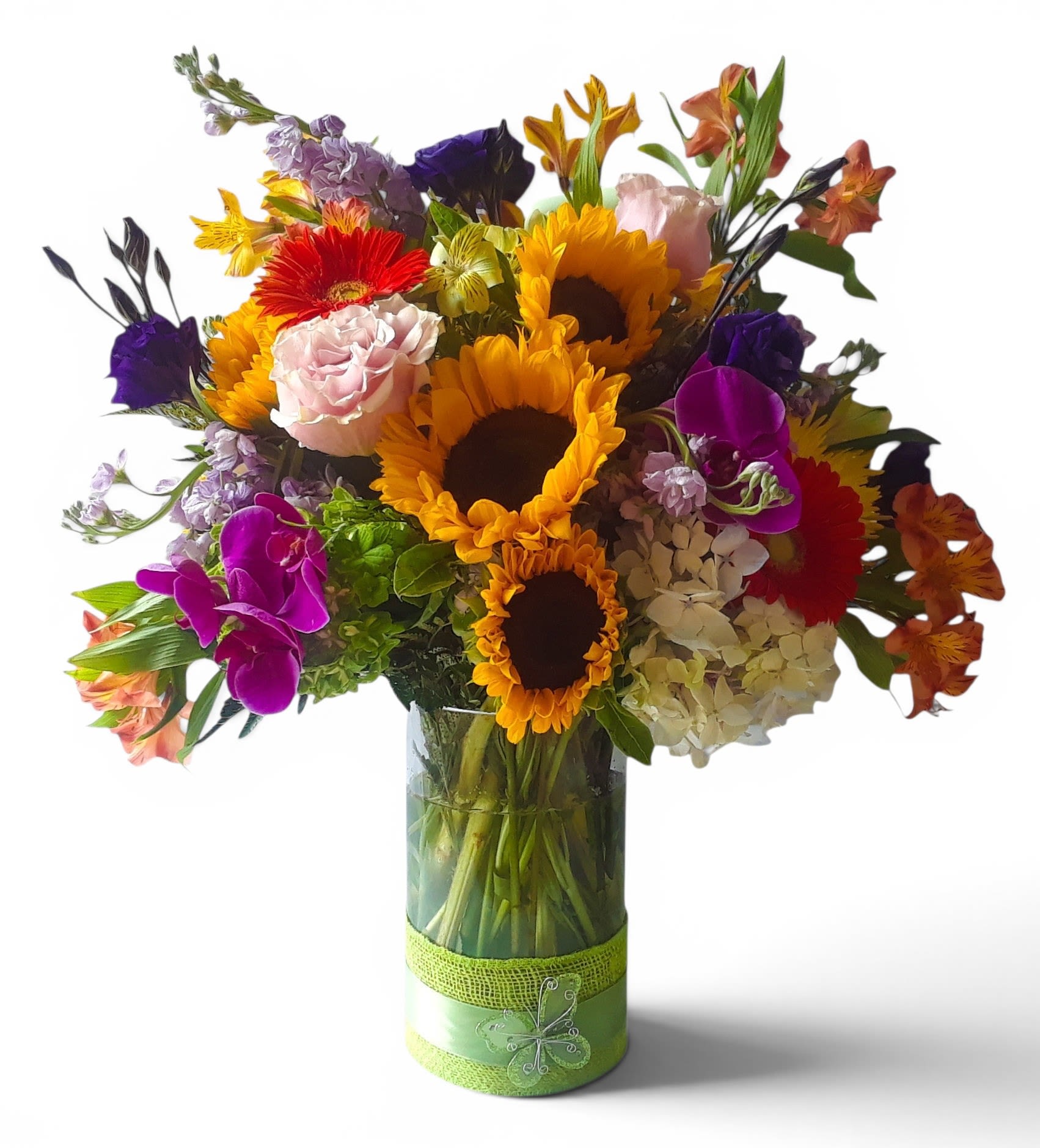 Vibrant Happy Birthday Bouquet - Mixed Sunflowers, Roses &amp; Orchids Arrangement - A dense, oversized mix of bright sunflowers, roses and Phalaenopsis orchids makes this birthday bouquet an unforgettable, celebratory statement - the kind of arrangement that makes the person you're thinking of feel truly seen on their special day. The Vibrant Happy Birthday Bouquet reads like a sunny garden in full swing: bold yellow sunflowers set a joyful tone while pink and purple roses and orchids add elegance and a touch of whimsy for a cheerful birthday gift.  Arranged in a clear glass vase with a green decorative ribbon and decorative wrap, this composition also includes hydrangeas, alstroemeria, gerbera daisies and stock for a lush, full shape and high-contrast palette of yellow, pink, purple, orange and white. The bouquet is generous and abundant, designed to sit center-table and brighten any room with layered textures - the round sunflower faces, soft rose petals, and sculptural Phalaenopsis orchids create visual depth and long-lasting appeal.  Perfect for birthdays, congratulations, or a thank-you that needs a little extra sparkle, this arrangement comes ready to display and will lift the recipient's spirits the moment it arrives. Care is simple: keep fresh water in the vase, trim stems if needed, and place away from direct heat to prolong blooms. Locally delivered in Haddon Township NS Haddonfield NJ, it's an instant, joyful way to say "happy birthday" or "I'm thinking of you."