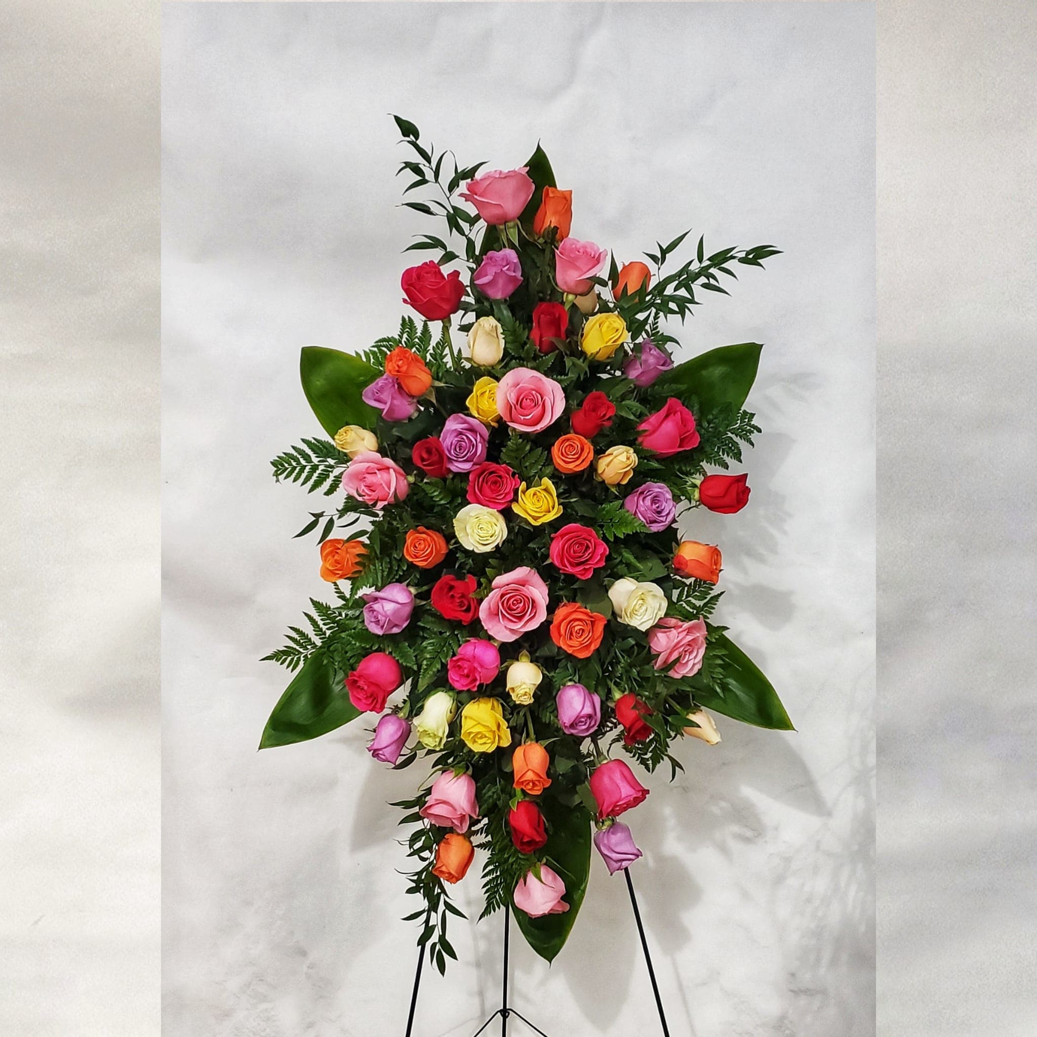 Tall standing spray of multicolored roses on an easel