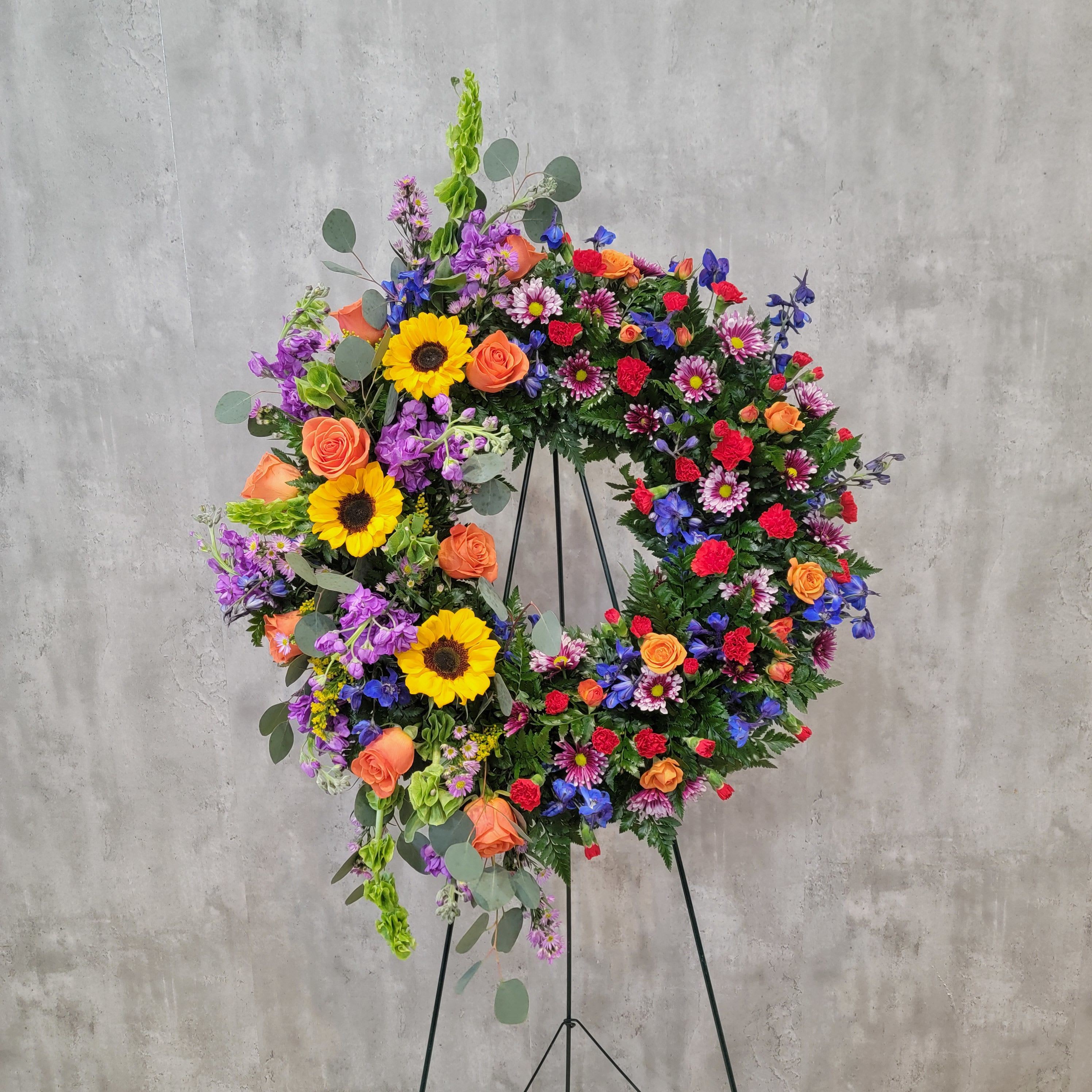 Large colorful floral wreath on a black stand