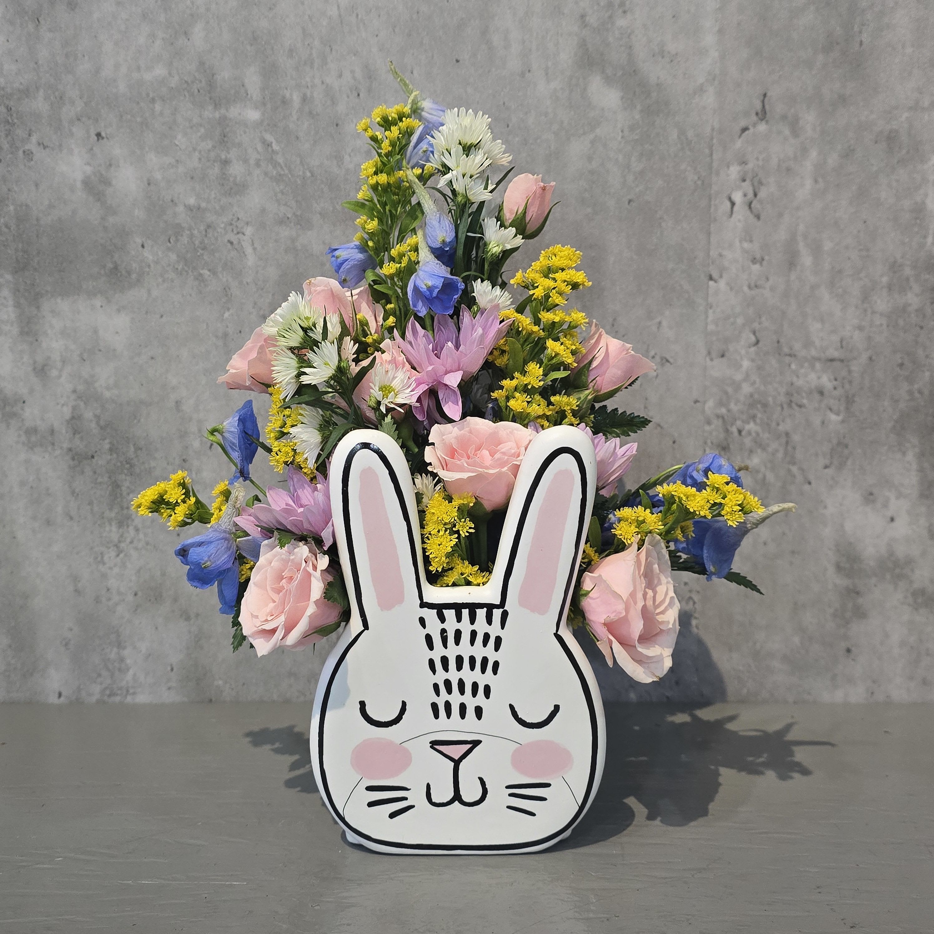 Mixed pastel flowers arranged in a bunny-shaped container