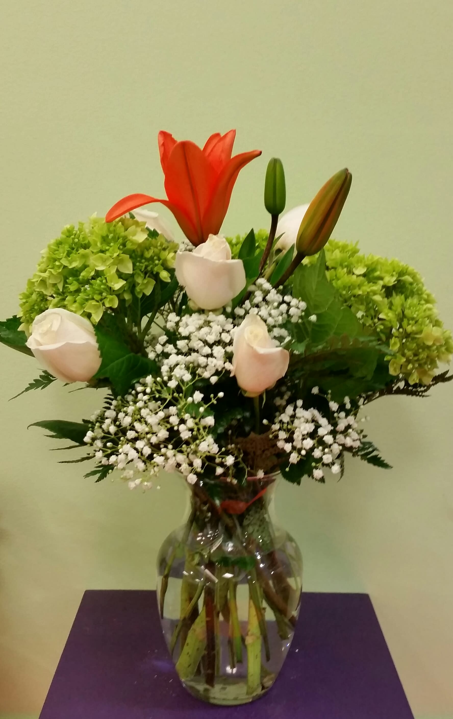 Bouquet of lilies, roses, hydrangeas, and baby's breath in a glass vase