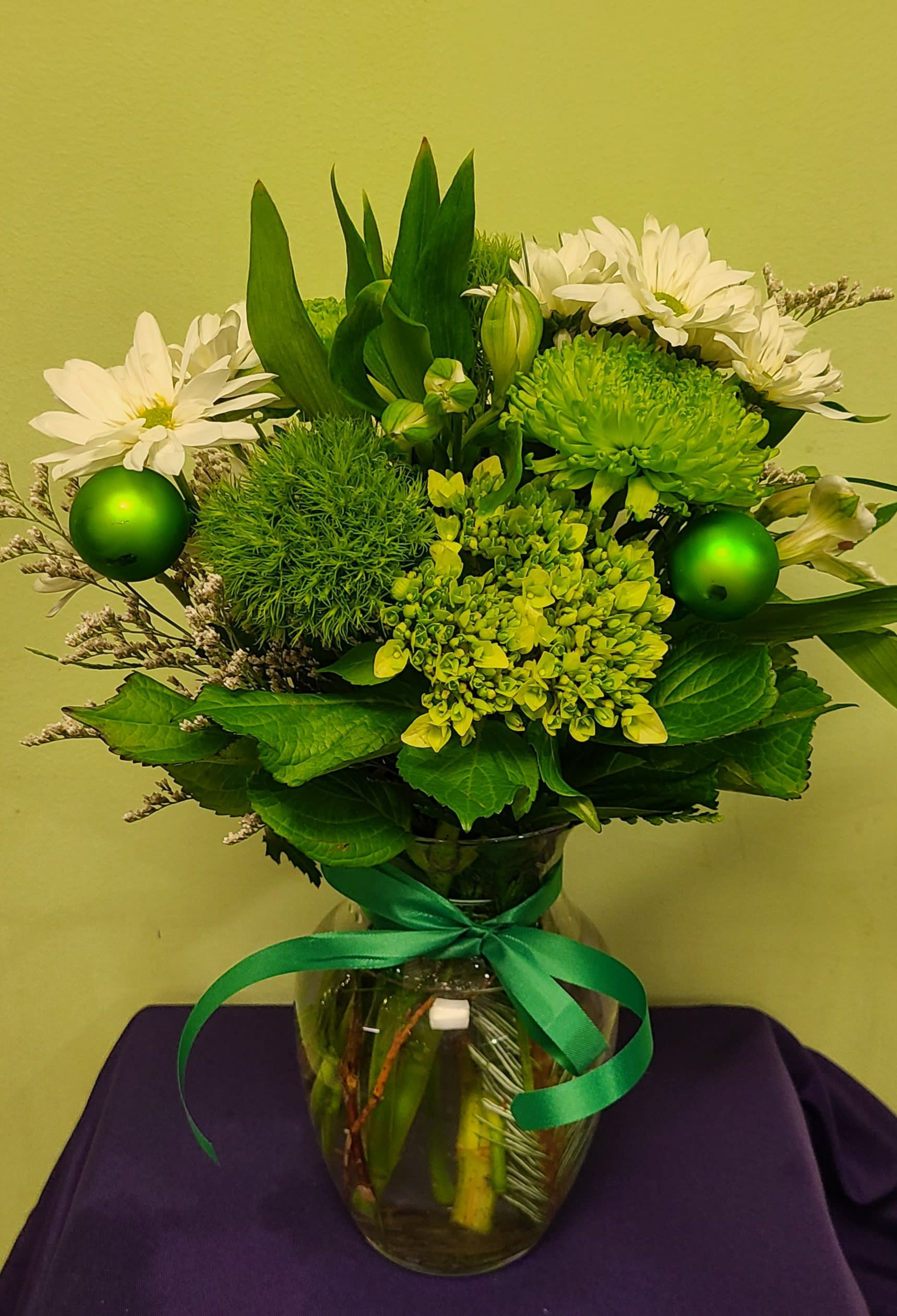 Green and white bouquet in a glass vase with a ribbon