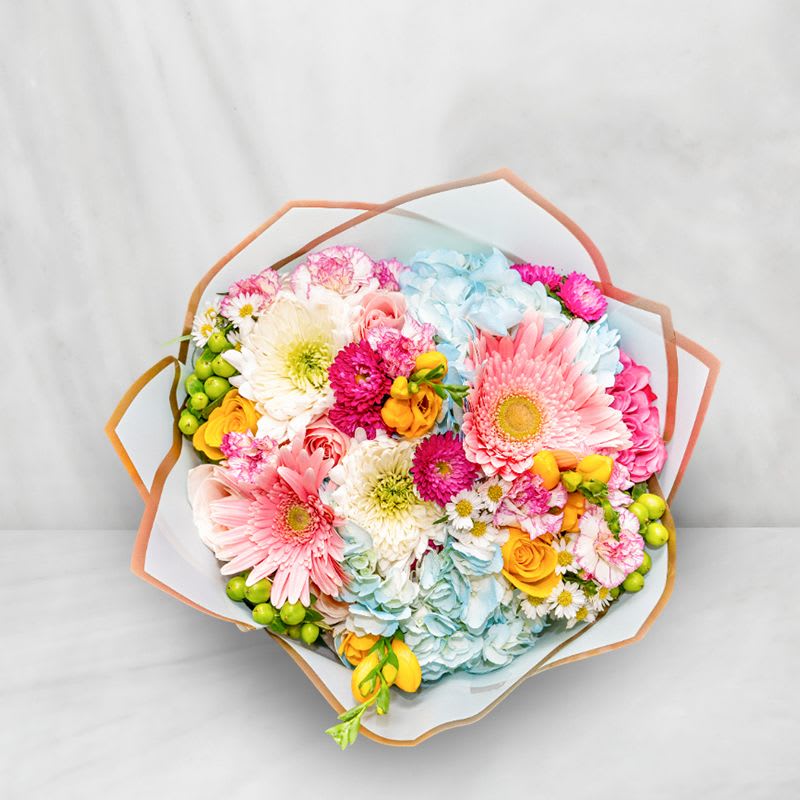 Colorful bouquet with gerbera daisies, roses, and hydrangeas wrapped in paper