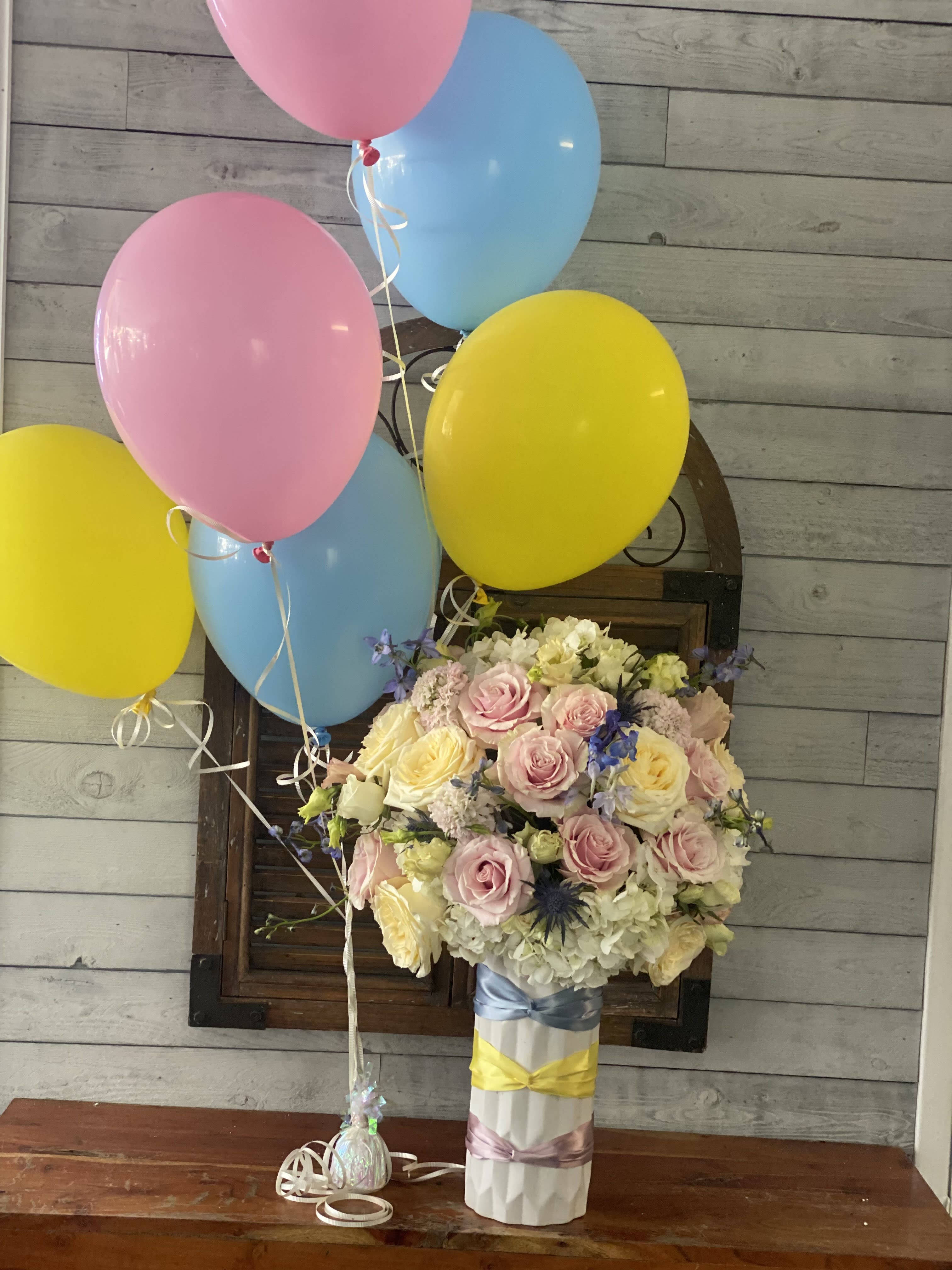 Pastel rose bouquet with pink, yellow, and blue balloons