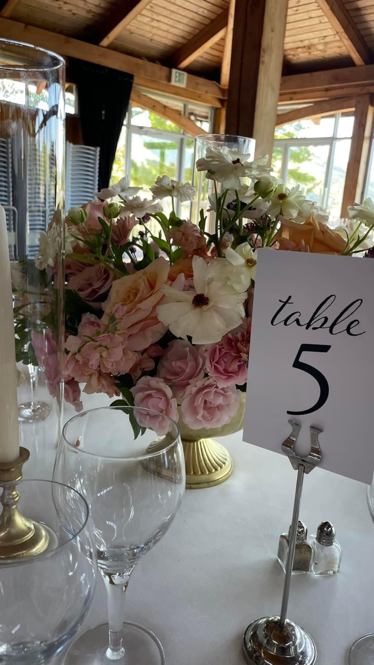 Pastel floral centerpiece in a gold vase beside a table number card