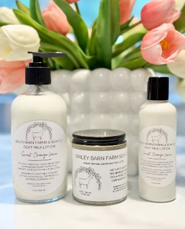 Tulips behind three goat milk skincare products on a white surface