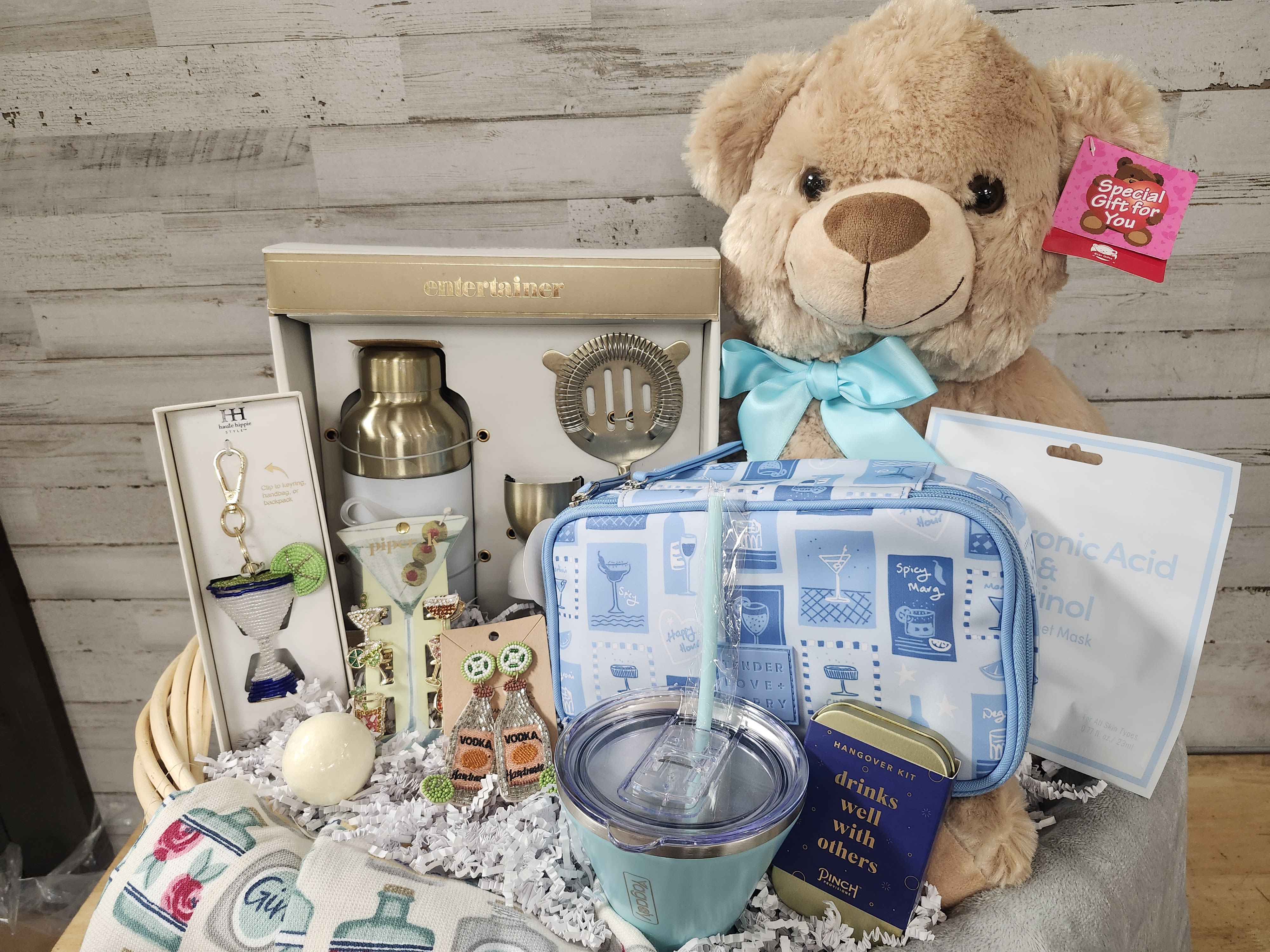 Cocktail Cutie - $250 - It may be 5 o'clock somewhere, but it will be nothing but happy hour when you send this cocktail themed gift basket.   The basket includes:  - Entertainer Cocktail Making Set      - Shaker, Strainer, &amp; Measuring Cup - Martini Style - Insulated Tumbler with Silicone Straw - Cocktail Theme - Hand Towels  - Hangover Kit - Cocktail Theme - Makeup Bag - Cocktail Theme - Rhinestone Hair Clips - Beaded Cocktail Bag Charm - Beaded Tequila Earrings - Bath Bomb - Face Mask  - Plush Teddy Bear 