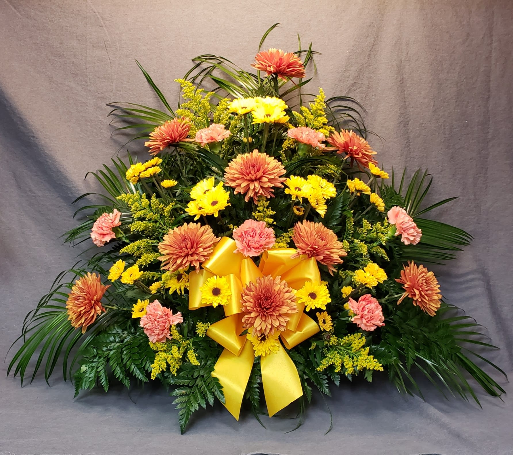 Large floral spray with yellow and peach flowers and a yellow ribbon