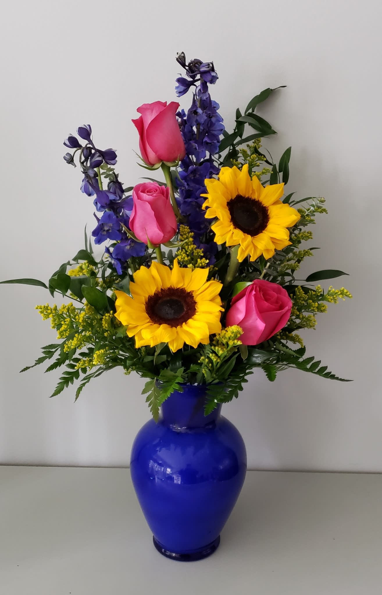 Bright in Blue - A cobalt blue vase full of bright florals. Sunflowers, , Roses, and much more!