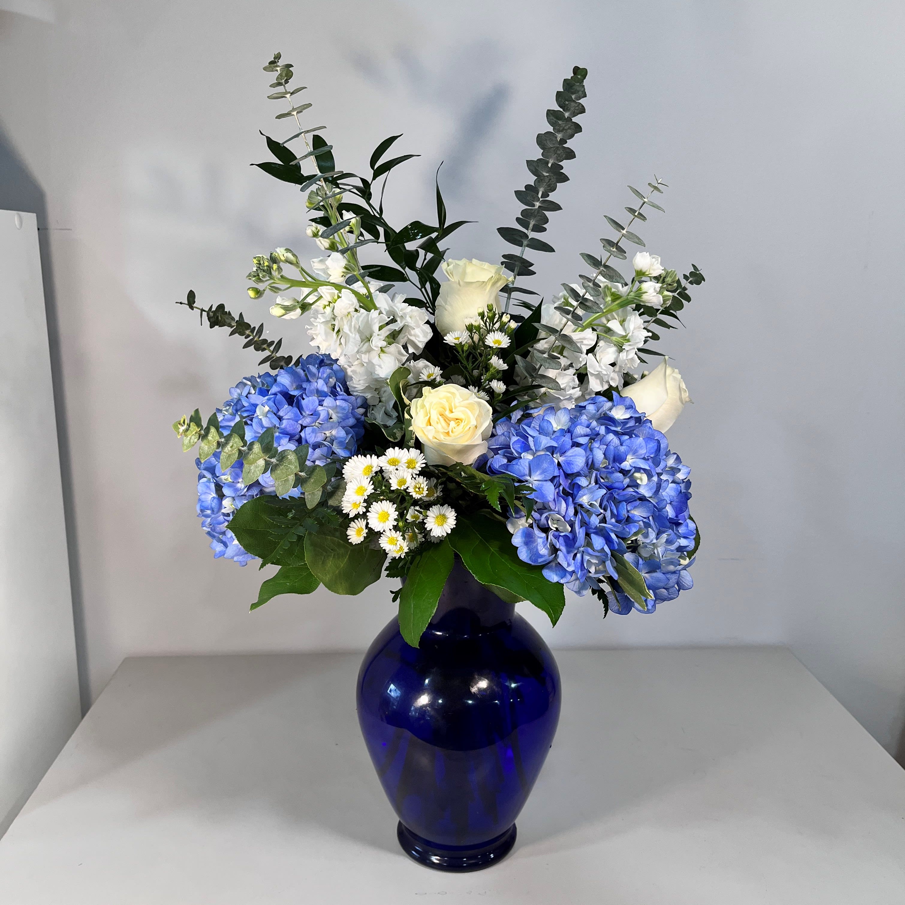 Blue and white floral arrangement in a cobalt vase