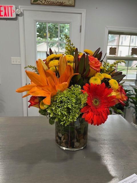 Bright mixed bouquet in a glass vase with orange lilies and red gerbera daisies