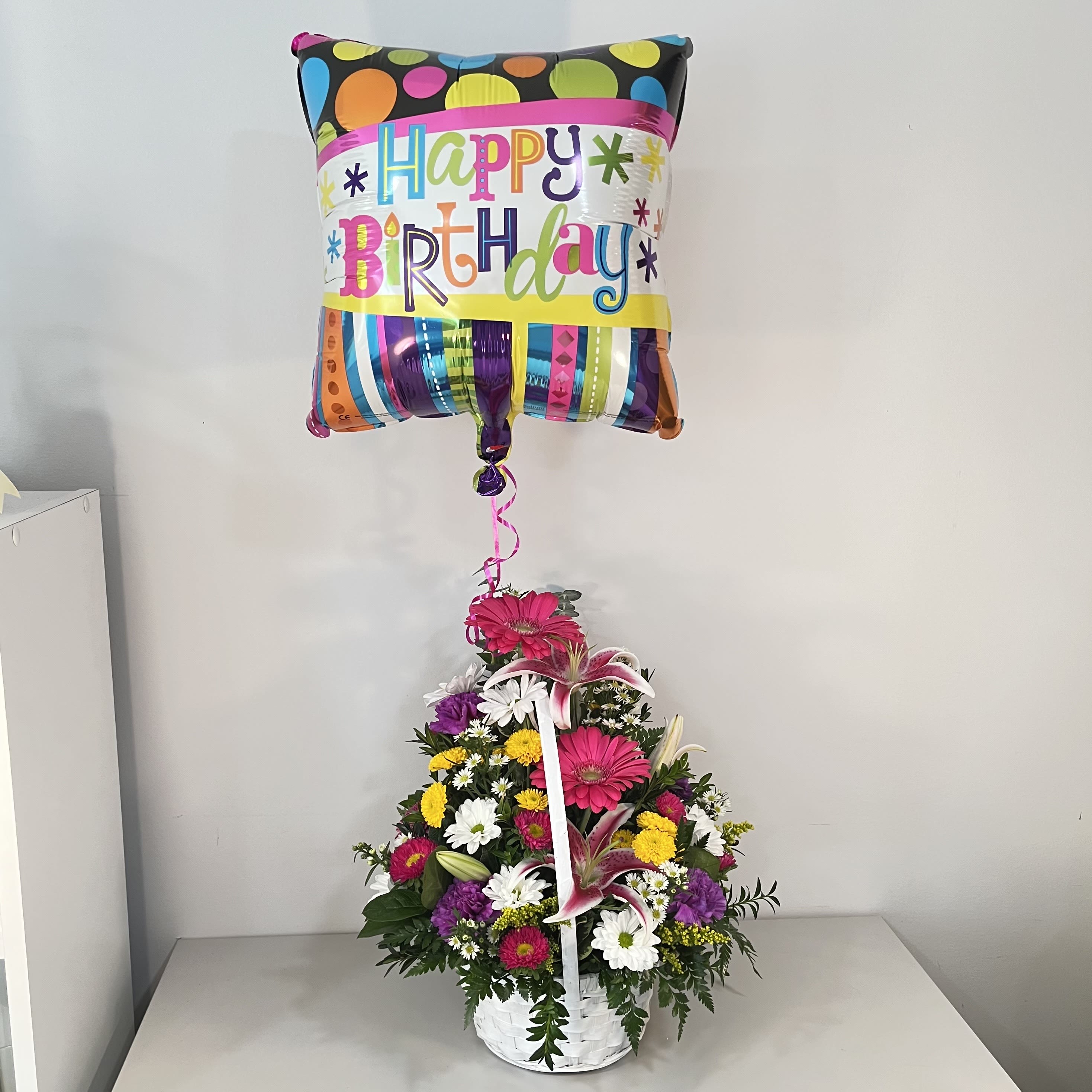 Happy Birthday Basket with Balloon - A basket brimming with our freshest daisy pompons, alstroemeria, an Asiatic lily and carnations, topped with a birthday balloon. The best gift for every age!