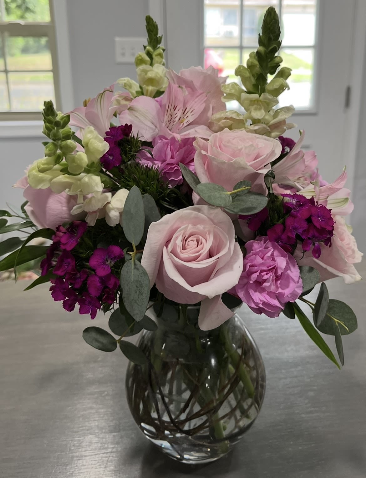 Pink roses and mixed blooms arranged in a glass vase