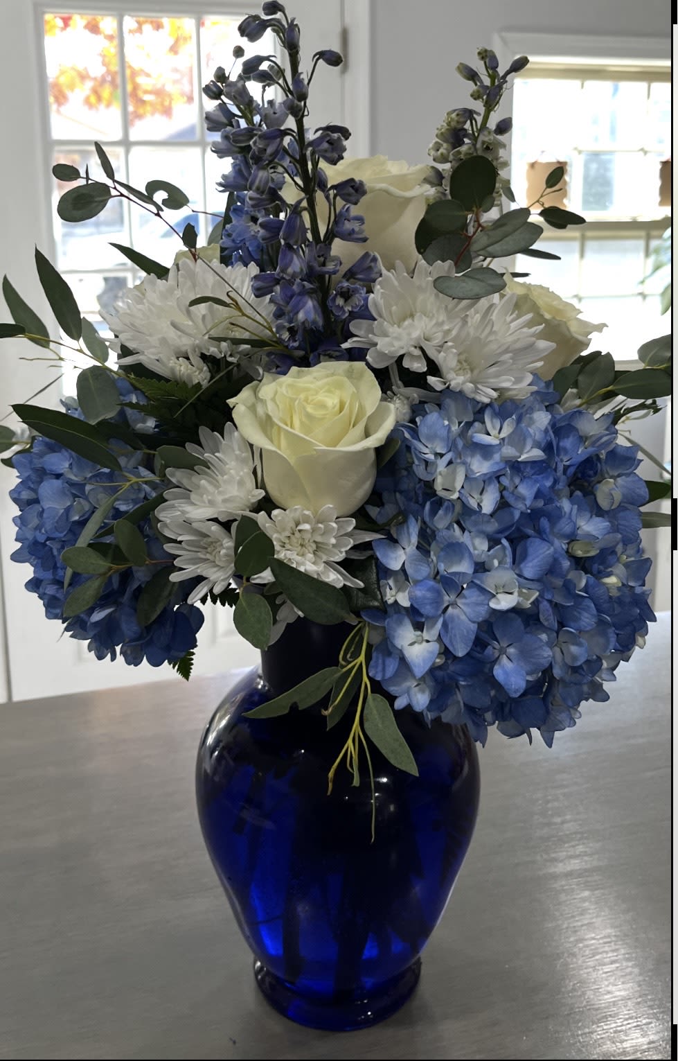 Beauty in Blue - This arrangement contains delphinium, Hydrangeas, Roses and Mums