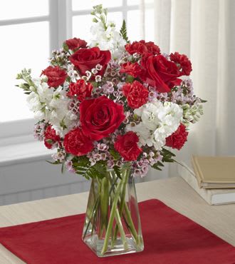 Red roses and white flowers arranged in a clear glass vase