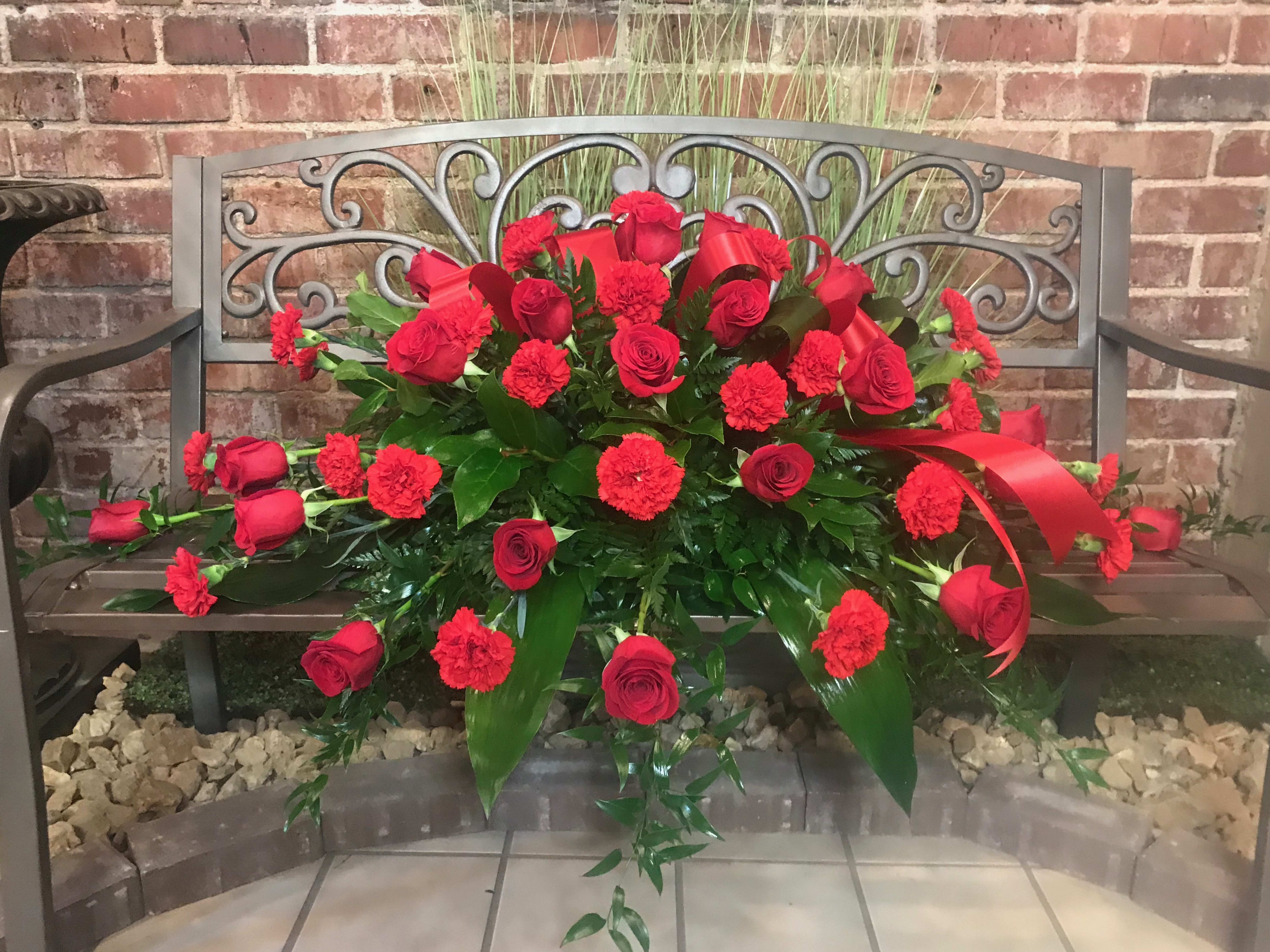 Red rose and carnation arrangement on a bench