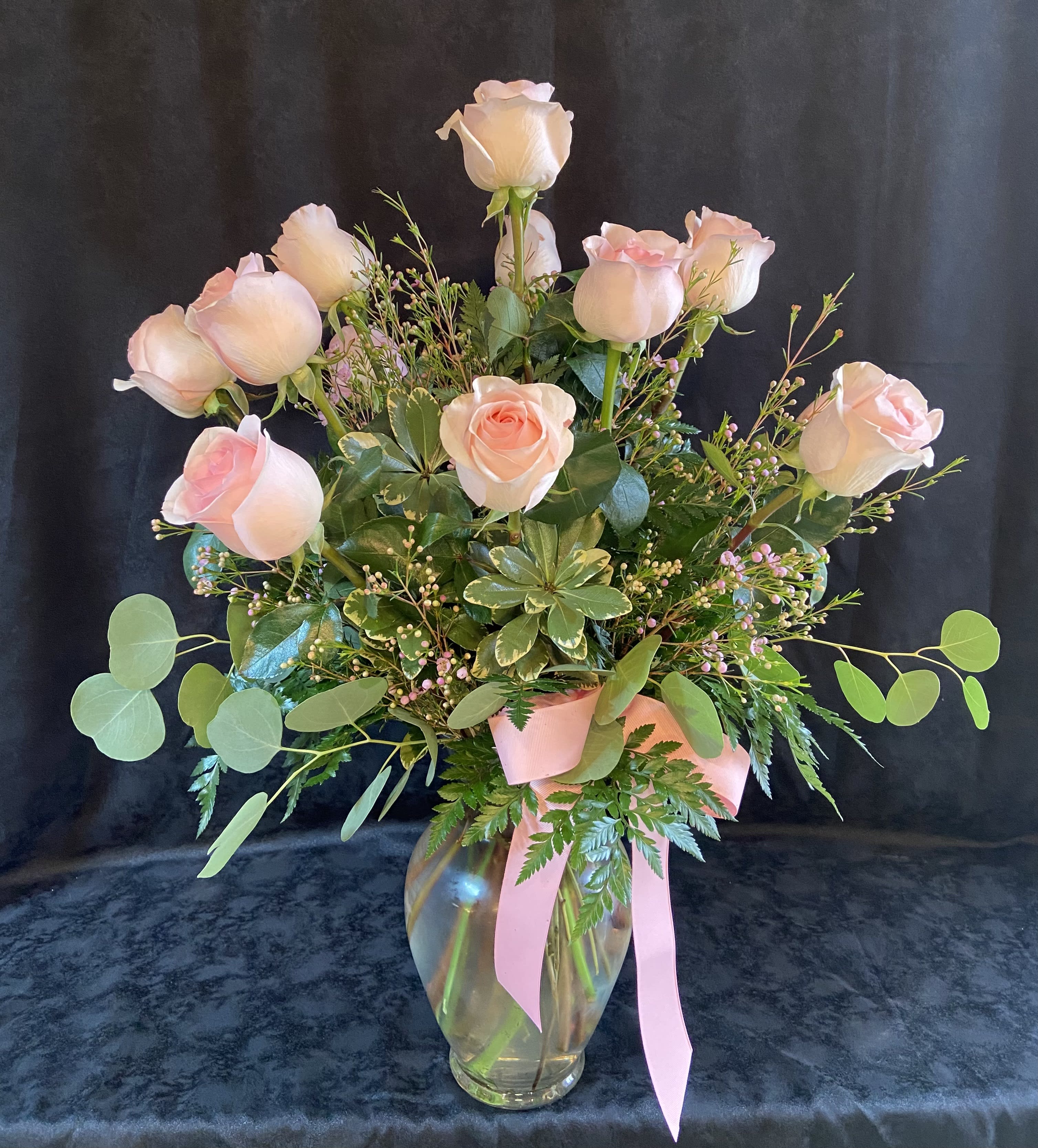 Pink roses in a glass vase with a pink ribbon