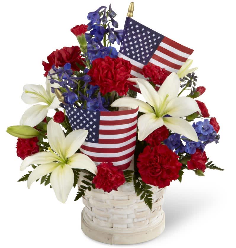 Red carnations and white lilies in a basket with small American flags